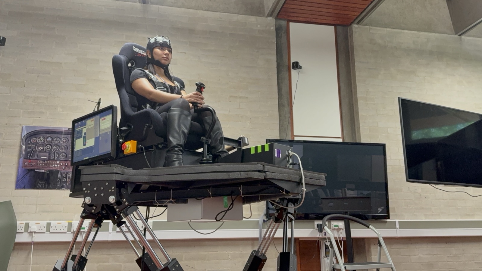 Participant wearing an EEG cap on a motion-platform flight simulator during a neuroscience and immersive-simulation study