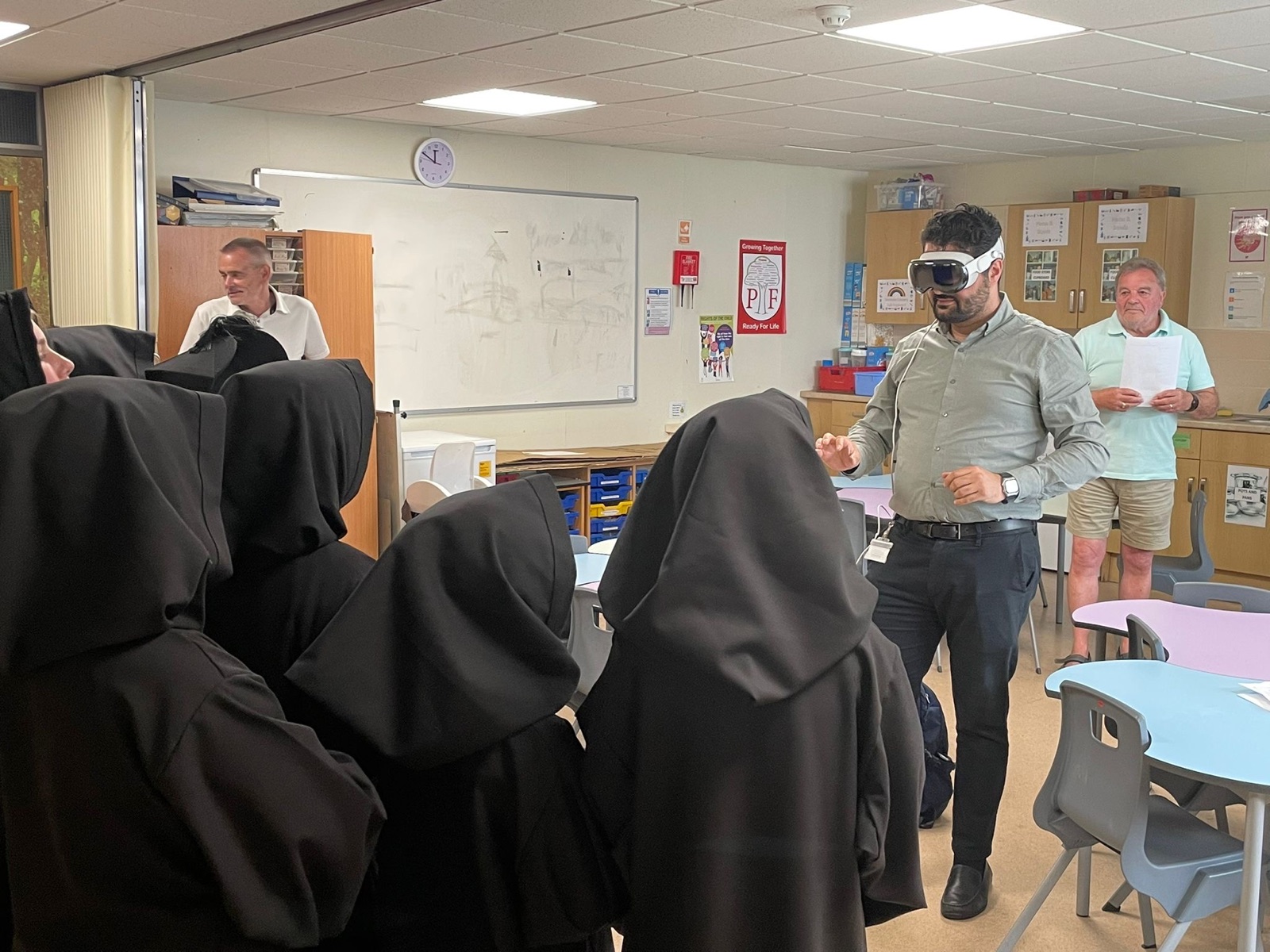 Diar demonstrating a mixed-reality headset to schoolchildren dressed in period costume